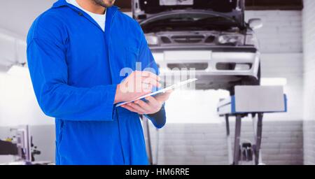 Mechanic writing on clipboard at garage Stock Photo