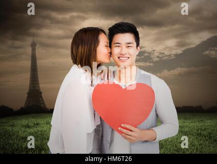 Woman kissing man while holding heart Stock Photo