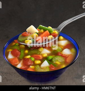 Hearty Vegetable Soup in blue bowl with spoon Stock Photo