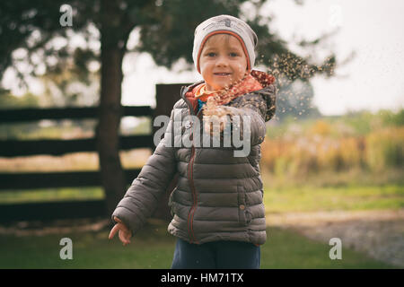A little boy playing outside in the country throwing grass seeds in the air Stock Photo