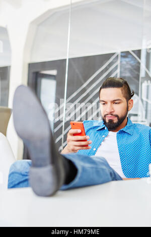 Student as start-up founder reading SMS on smartphone Stock Photo