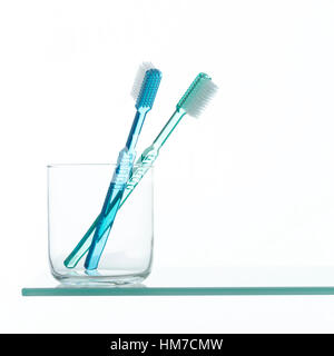Toothbrushes in glass on shelf Stock Photo
