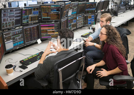 Group of young people analyzing stock market data at trading desk Stock Photo