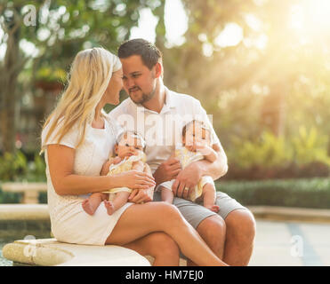 Happy family with two baby girls (2-5 months) at park in sunlight Stock Photo