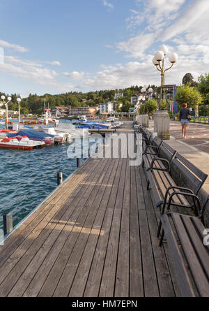 VELDEN, AUSTRIA - SEPTEMBER 8, 2015: People walk along Worthersee lake waterfront with moored boats. It is a market town in state of Carinthia, one of Stock Photo