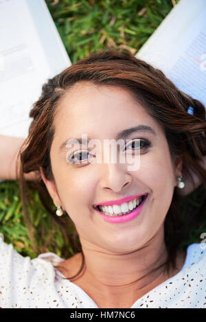 happy smiling  girl lay on grass with books Stock Photo