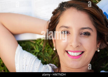 happy smiling woman lay on books and grass Stock Photo