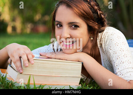 woman resting on pile of books and smiling Stock Photo
