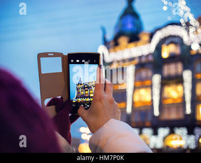 Woman taking pictures of Book Home Zinger Building by her Smartphone in Saint Petersburg Stock Photo
