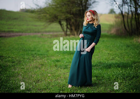 Yong elegance blonde girl at green dress on the garden in spring. Stock Photo