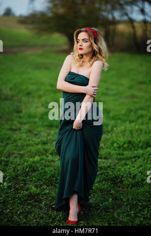 Yong elegance blonde girl at green dress on the garden in spring. Stock Photo