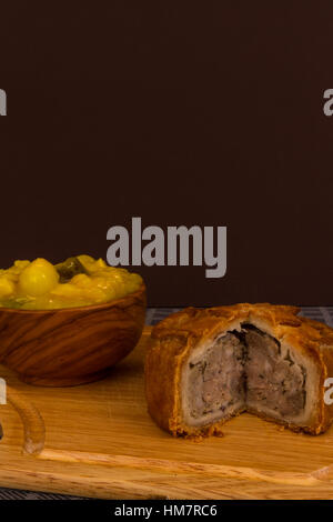 Piccalilli relish in a wooden bowl on a board. Stock Photo