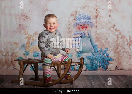baby girl on sledge in winter time in studio Stock Photo