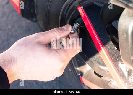 Man opening valve tire cap of car wheel to check air pressure Stock Photo