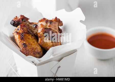 Asian chicken wings and noodles in take-out box with dipping sauce Stock Photo