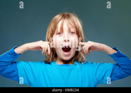 Boy Putting his Index Fingers in his Ears not to Hear Stock Photo