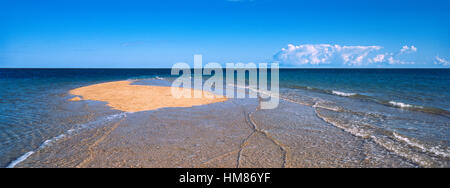 The rising tide swallows a small sand island. Stock Photo