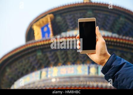 Closeup of man using a smart phone over Chinese temple background Stock Photo