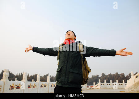 Asian man stretching arms wide open in Chinese architecture with blue sky and copy space Stock Photo