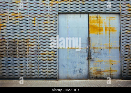Rusty metal gate locked with security padlock and rusty metal wall around Stock Photo