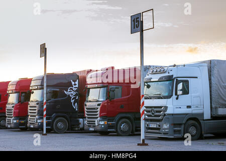 Narva, Estonia - August 20, 2016: Scania & Mercedes heavy trucks loaded with goods trailers, parked in waiting area on Estonian-Russian state border c Stock Photo