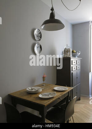 Interior of a house,  a small table set up, kitchen with two Fornasetti dishes on the wall Stock Photo