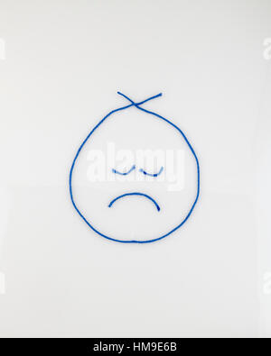 A sad face shaped from blue yarn. on a white background. Cutout. Illustration. Concept, conceptual. Stock Photo