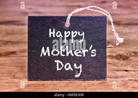 Happy Mothers Day written on chalk board on wooden table Stock Photo
