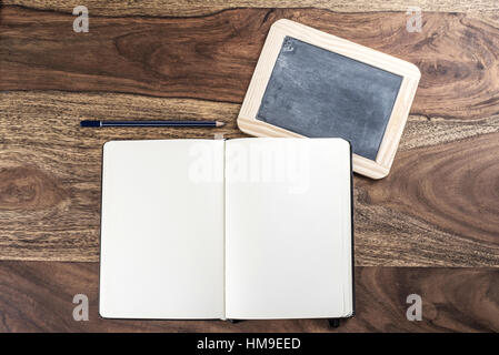open plain empty page notebook with pencil and blackboard on rustic wood table Stock Photo