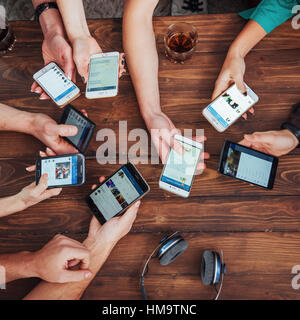 Top view hands circle using phone in cafe - Multiracial friends mobile addicted interior scene from above - Wifi connected people in bar table meeting - Concept of teamwork Stock Photo