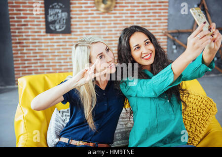 Two beautiful young woman doing selfie in a cafe, best friends girls together having fun, posing emotional lifestyle people concept Stock Photo