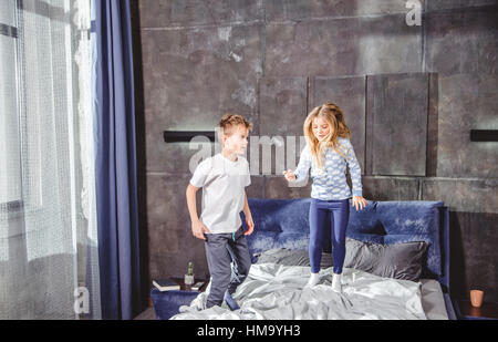 Siblings jumping on bed Stock Photo