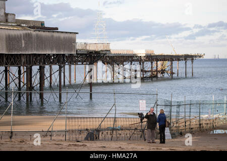 Visitors to Cowlyn Bay looking on to view parts of the Victoria Pier had fallen into the sea during the day with more expected Stock Photo