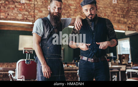 Shot of barber with stylish young man standing at salon. Two men standing at barber shop. Stock Photo