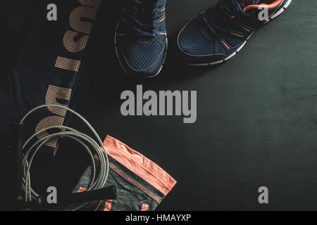 Top view of women's dark blue and pink workout outfit with a skipping rope on a black background Stock Photo