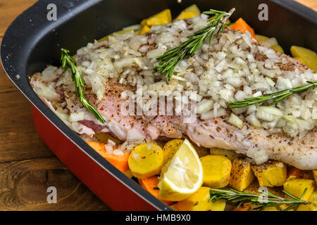 Raw lamb shank with roots and onion ready for frying on a rustic wooden board. Close view Stock Photo