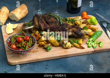 Roast shoulder of lamb on baked potato and carrots, wooden board, top view Stock Photo