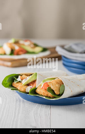Fish finger wraps with avocado and tomato serves on blue plate Stock Photo