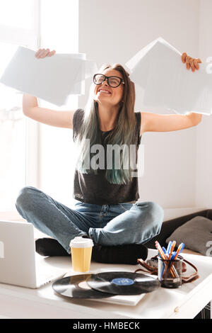 Happy excited young woman sitting on the table and celebrating success Stock Photo