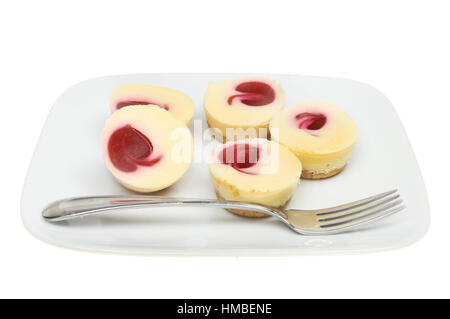 Individual raspberry cheesecakes with a fork on a plate isolated against white Stock Photo