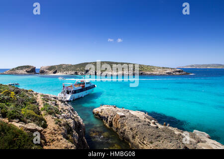The sunny blue lagoon in Comino, Malta. Crystal clear sunny Mediterranean sea, with a rock and sand on the photo. Stock Photo