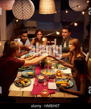 Friends making a toast at a patio dinner party, vertical Stock Photo