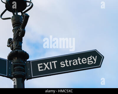 Street lighting pole with conceptual message Exit Strategy on directional arrow over blue cloudy background. Stock Photo
