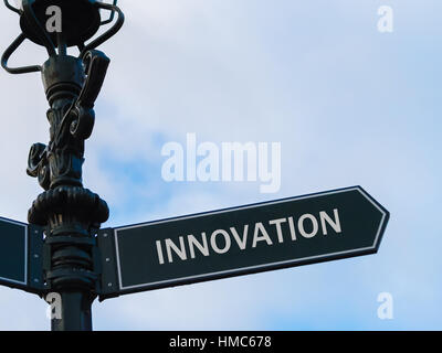 Street lighting pole with conceptual message INNOVATION on directional arrow over blue cloudy background. Stock Photo