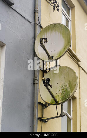 Two old satellite dishes on the wall of a domestic property in Ireland. Stock Photo