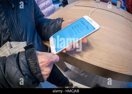 A shopper tries out an iPhone 7 Plus in the temporary Apple store on Fifth Avenue in New York while the original store undergoes renovation on Monday, January 30, 2017. Apple is scheduled to release its fourth quarter results which include what analysts' predict are strong sales of the iPhone 7. (© Richard B. Levine) Stock Photo