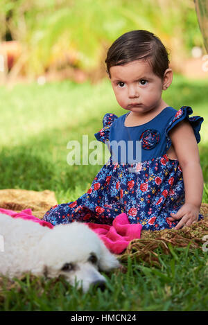 serious angry little girl with dog in green garden Stock Photo