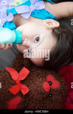 small girl drink milk with teddy bear view from above Stock Photo