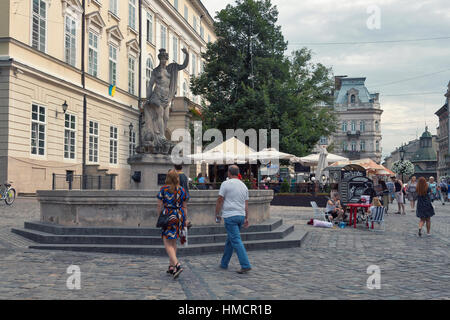 LVIV, UKRAINE - JULY 29, 2014: Pedestrians walk in front of ancient statue of Amphitrite on Market (Rynok) Square, the central square and most popular Stock Photo