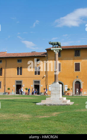 PISA, ITALY - SEPTEMBER 04, 2014: Unrecognizable tourists walk and make photos along statue of wolf with Romulus and Remus and ancient building with t Stock Photo